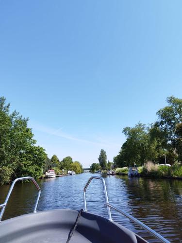 a boat on a river with trees on the side at Ferienhaus Am Fehntjer Tief in Emden