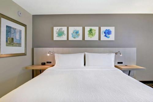 a bedroom with a large white bed with two tables at Hilton Garden Inn Orlando Lake Buena Vista in Orlando