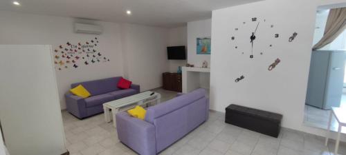 a living room with two purple couches and a clock at Salentum Villa Miami - con ampia terrazza in Vignacastrisi