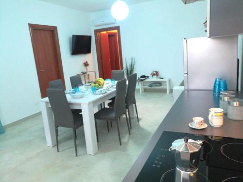 a kitchen with a white table with chairs and a refrigerator at Casa Leukos Salento - con terrazza privata in Vignacastrisi