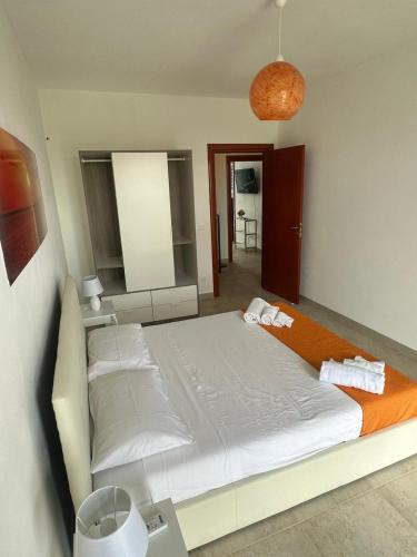 a bedroom with a large white bed with an orange blanket at Casa Leukos Salento - con terrazza privata in Vignacastrisi