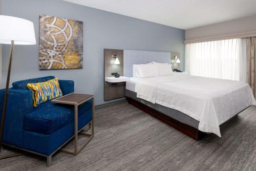 a hotel room with a bed and a blue chair at Hampton Inn & Suites Country Club Plaza in Kansas City