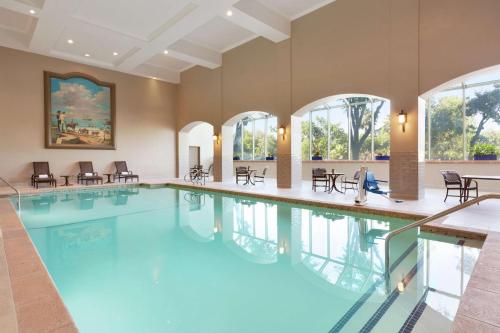 una gran piscina con sillas, mesas y ventanas en Embassy Suites by Hilton Milpitas Silicon Valley, en Milpitas