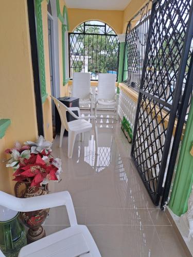 Un balcón con sillas blancas y una mesa. en Casa de Marilyn en Andrés