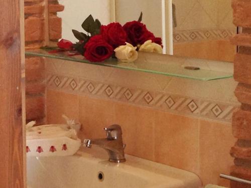 lavabo en el baño con espejo y rosas rojas en un estante en LA CASA DEI POETI - C.I.R. 054039LOTUR19934, en Perugia