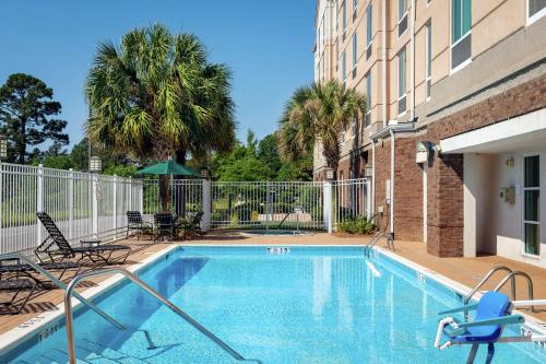 a swimming pool with chairs and a building at Hilton Garden Inn Mobile West I-65 Airport Boulevard in Mobile