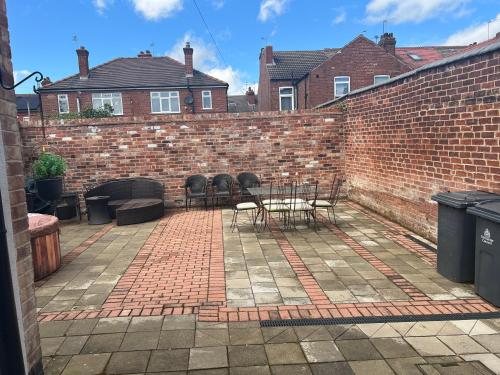 a brick wall with a table and chairs on a patio at The Little Hexthorpe house in Doncaster