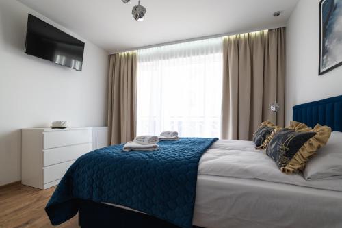a bedroom with a bed with a blue blanket and a window at SOLEK Apartamenty i pokoje gościnne in Mielno