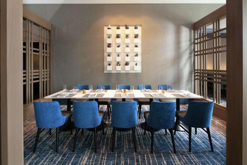 a dining room with a large table and blue chairs at Hilton Madison Monona Terrace in Madison