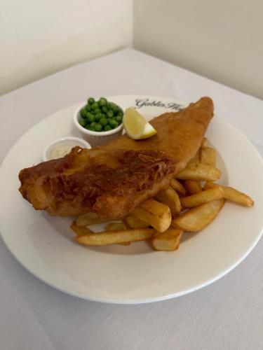 une plaque avec du poisson et des frites et une face de pois dans l'établissement The Gables Hotel, à Gretna Green