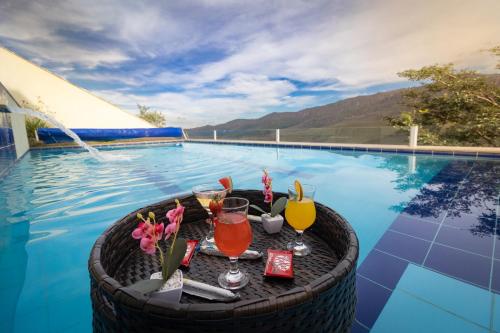 uma piscina com uma mesa com bebidas e flores em Até 8 Hóspedes, Linda Vista, Piscina, Salão de Jogos e Brinquedoteca em Ouro Preto