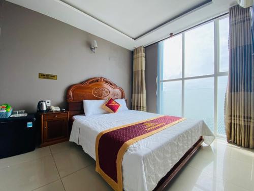 a bedroom with a bed and a large window at Golden Hotel in Vung Tau