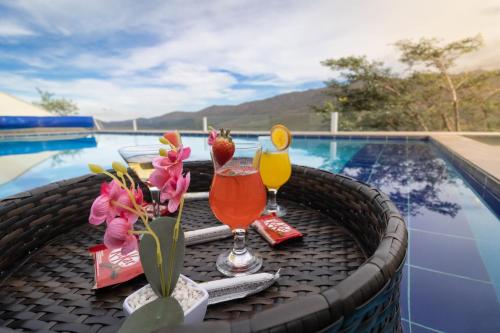 a table with two drinks and flowers on it next to a swimming pool at Até 8 Hóspedes, Piscina Panorâmica, Salão de Jogos Premium e Brinquedoteca in Ouro Preto