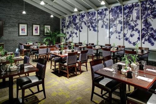 a restaurant with wooden tables and chairs and large windows at Hilton Garden Inn New York/Manhattan-Chelsea in New York