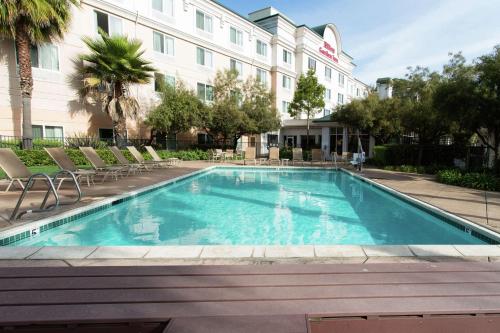 a swimming pool in front of a hotel with chairs at Hilton Garden Inn Fairfield in Fairfield