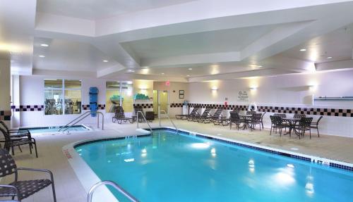 einen Pool in einem Hotel mit Stühlen und Tischen in der Unterkunft Hilton Garden Inn Oklahoma City Midtown in Oklahoma City