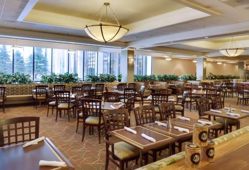 ein Esszimmer mit Tischen und Stühlen und Fenstern in der Unterkunft DoubleTree by Hilton Hotel & Executive Meeting Center Omaha-Downtown in Omaha