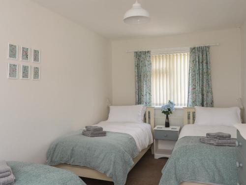 a bedroom with two twin beds and a window at Glan Awel in Pwllheli
