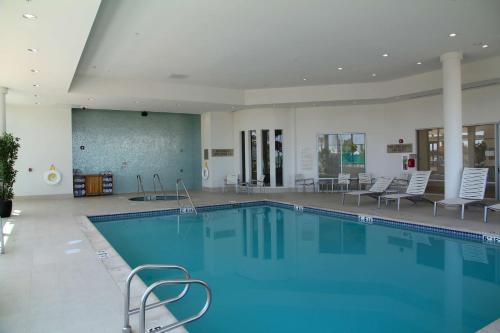 a large swimming pool with chairs and a table at Embassy Suites Ontario - Airport in Ontario