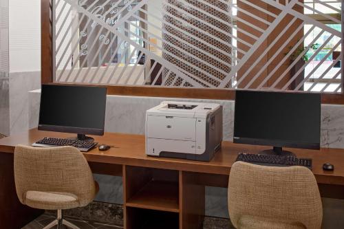 two computer monitors and a printer on a desk at DoubleTree by Hilton Irvine Spectrum in Irvine