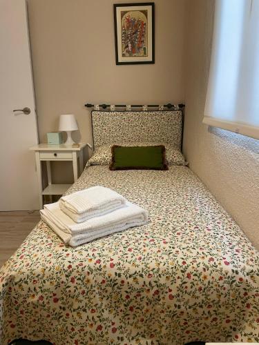 a bed with a green pillow and towels on it at Cal Xambu in Cambrils