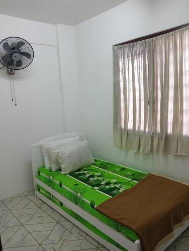 a bed in a room with a window and a fan at KHAIRUL HOMESTAY SEBERANG JAYA in Kampong Telok