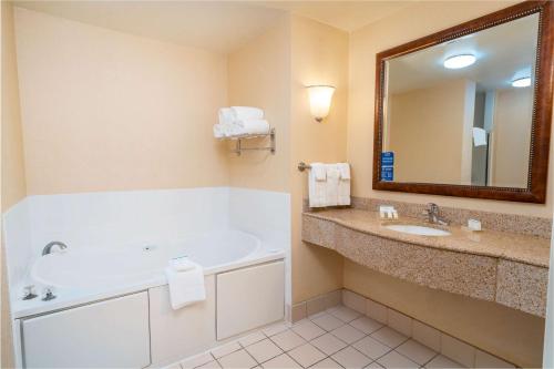 a bathroom with a tub and a sink and a mirror at Hilton Garden Inn Ontario Rancho Cucamonga in Rancho Cucamonga