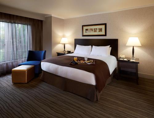 クレアモントにあるダブル ツリー バイ ヒルトン クレアモントの大きなベッドと青い椅子が備わるホテルルームです。