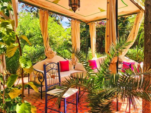 eine Veranda mit 2 Stühlen und einem Bett im Garten in der Unterkunft Villa mogador in Essaouira