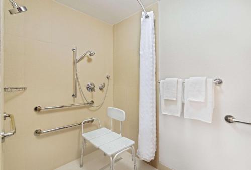 y baño con silla blanca y ducha. en DoubleTree by Hilton Orlando East - UCF Area en Orlando