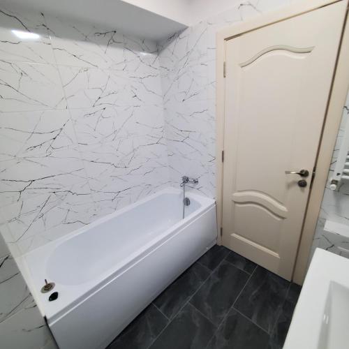 a bathroom with a white tub and marble walls at Luxury Apartament Bacovia in Bacău