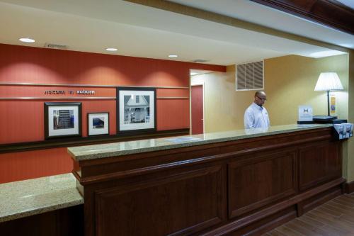 a man standing at a bar in a waiting room at Hampton Inn Auburn in Auburn