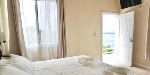 a bedroom with a white bed and a large window at Ocean View Hotel and Restaurant in Roatán