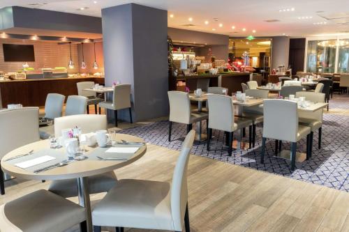 restauracja ze stołami i krzesłami oraz bar w obiekcie Hilton Paris La Défense w mieście Puteaux