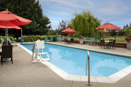 a large swimming pool with chairs and umbrellas at TownePlace Suites by Marriott Portland Vancouver in Evergreen