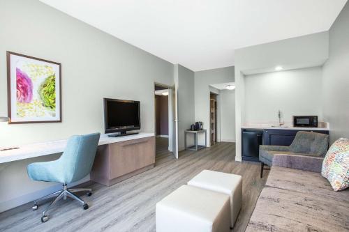 a living room with a couch a desk and a tv at Hilton Garden Inn Palm Beach Gardens in Palm Beach Gardens