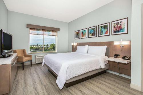 a bedroom with a bed and a desk and a television at Hilton Garden Inn Palm Beach Gardens in Palm Beach Gardens