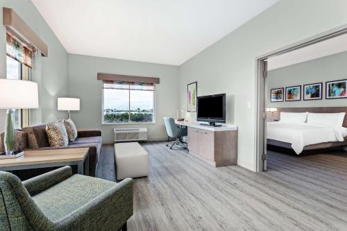 a living room with a bedroom and a bed and a tv at Hilton Garden Inn Palm Beach Gardens in Palm Beach Gardens