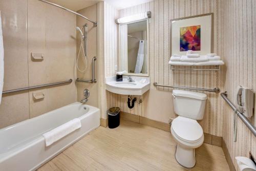 a bathroom with a toilet and a sink and a tub at Hilton Garden Inn Portland Airport in Portland