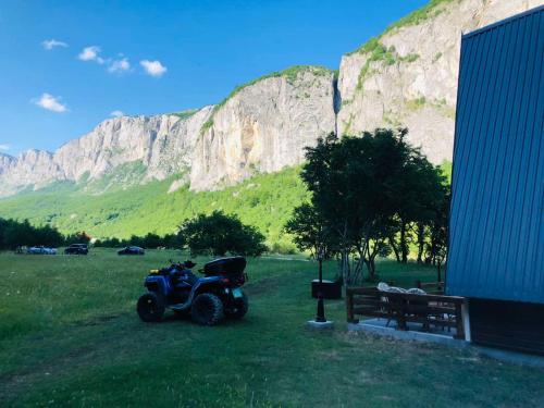 a motorcycle parked in a field in front of a mountain at Family S house - Komarnica in Šavnik