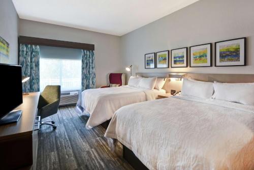 a hotel room with two beds and a flat screen tv at Hilton Garden Inn Panama City in Panama City