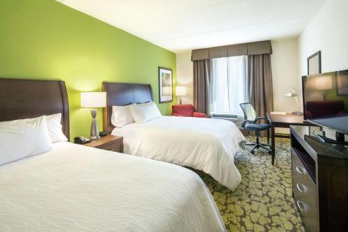 a hotel room with two beds and a flat screen tv at Hilton Garden Inn Pascagoula in Pascagoula