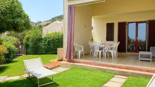 un patio con sedie bianche, tavolo ed erba di Villetta Turagri 22 a soli 300 m dalla spiaggia 10 posti letto a Costa Rei