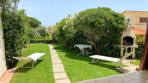 un giardino con panchina e griglia sull'erba di Villetta Turagri 22 a soli 300 m dalla spiaggia 10 posti letto a Costa Rei
