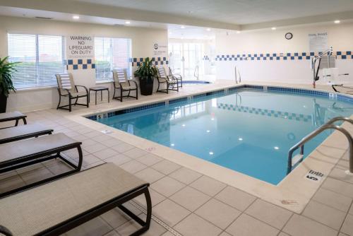 a large pool in a hotel with chairs and tables at Hilton Garden Inn Kennett Square in Kennett Square