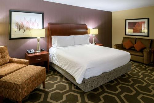 a hotel room with a large bed and a chair at Hilton Garden Inn Kennett Square in Kennett Square