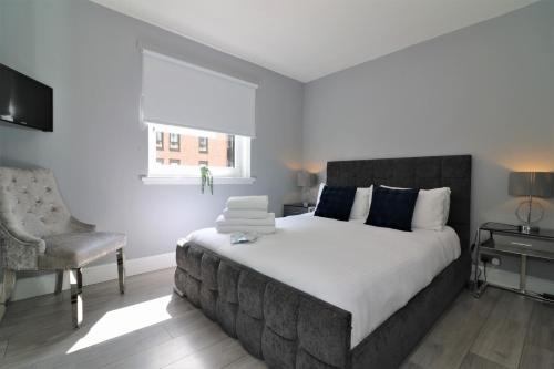 a bedroom with a large bed and a chair at 2 Bedroom Apartment at SECC Hydro FREE PARKING in Glasgow
