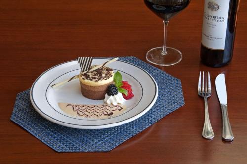 a plate with a dessert on a table with a wine glass at Hilton Phoenix Airport in Phoenix