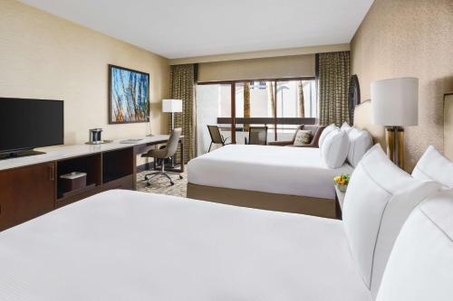 a hotel room with two beds and a desk at Hilton Phoenix Airport in Phoenix