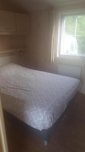 a bed in a bedroom with a window at Waterchalet number 6 Recreationpark Yn'e Lijte Grou met ligplaats boot in Grou